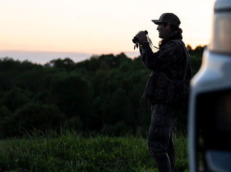 Hunter looking through Bushnell Binoculars in early morning sunlight